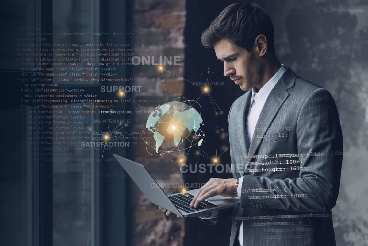 A businessman using a laptop with a digital holographic globe and connectivity graphics overlay.