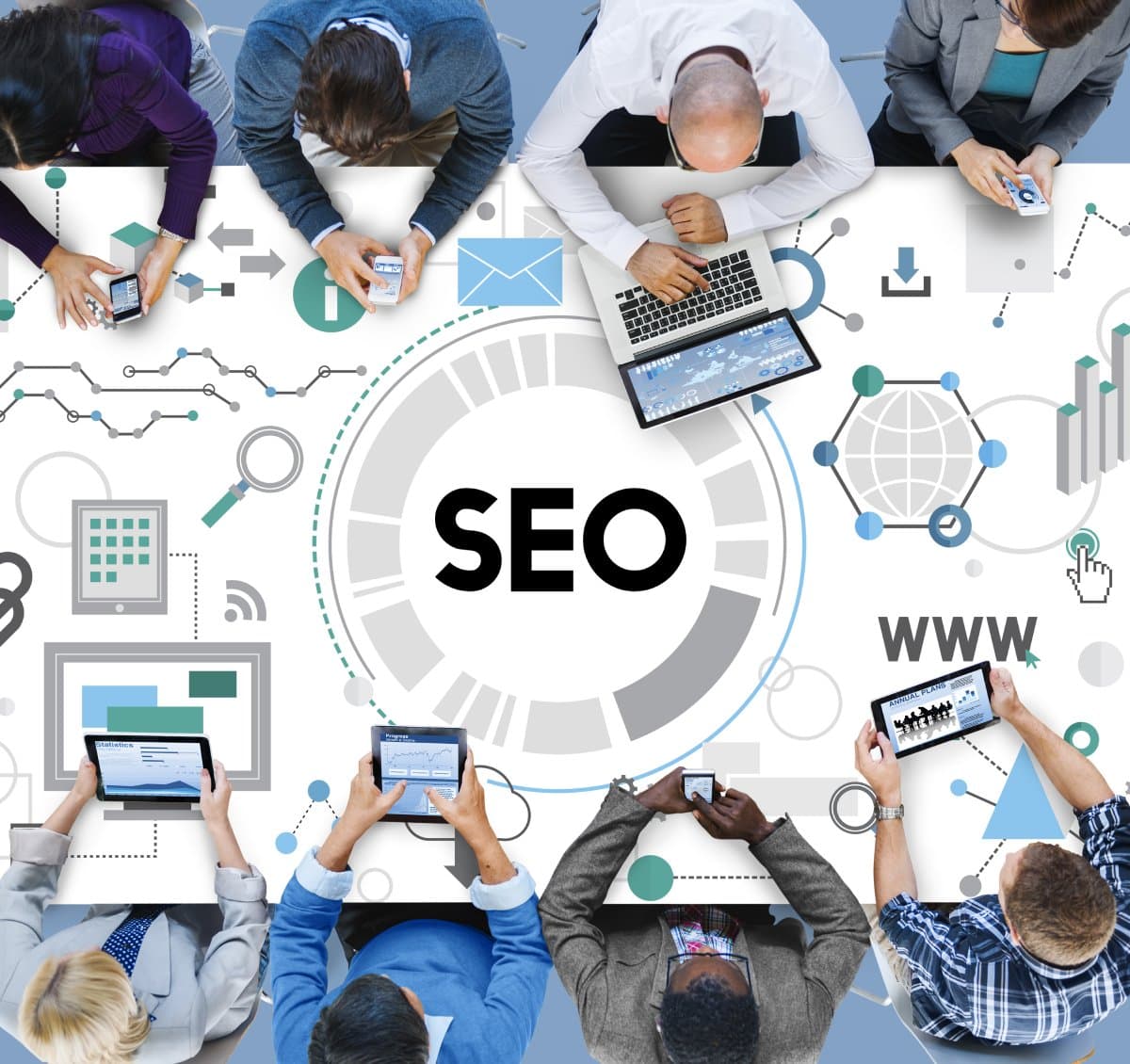 Top view of diverse group of professionals around a table, working on laptops and tablets, focused on SEO strategies. Icons symbolize digital concepts.