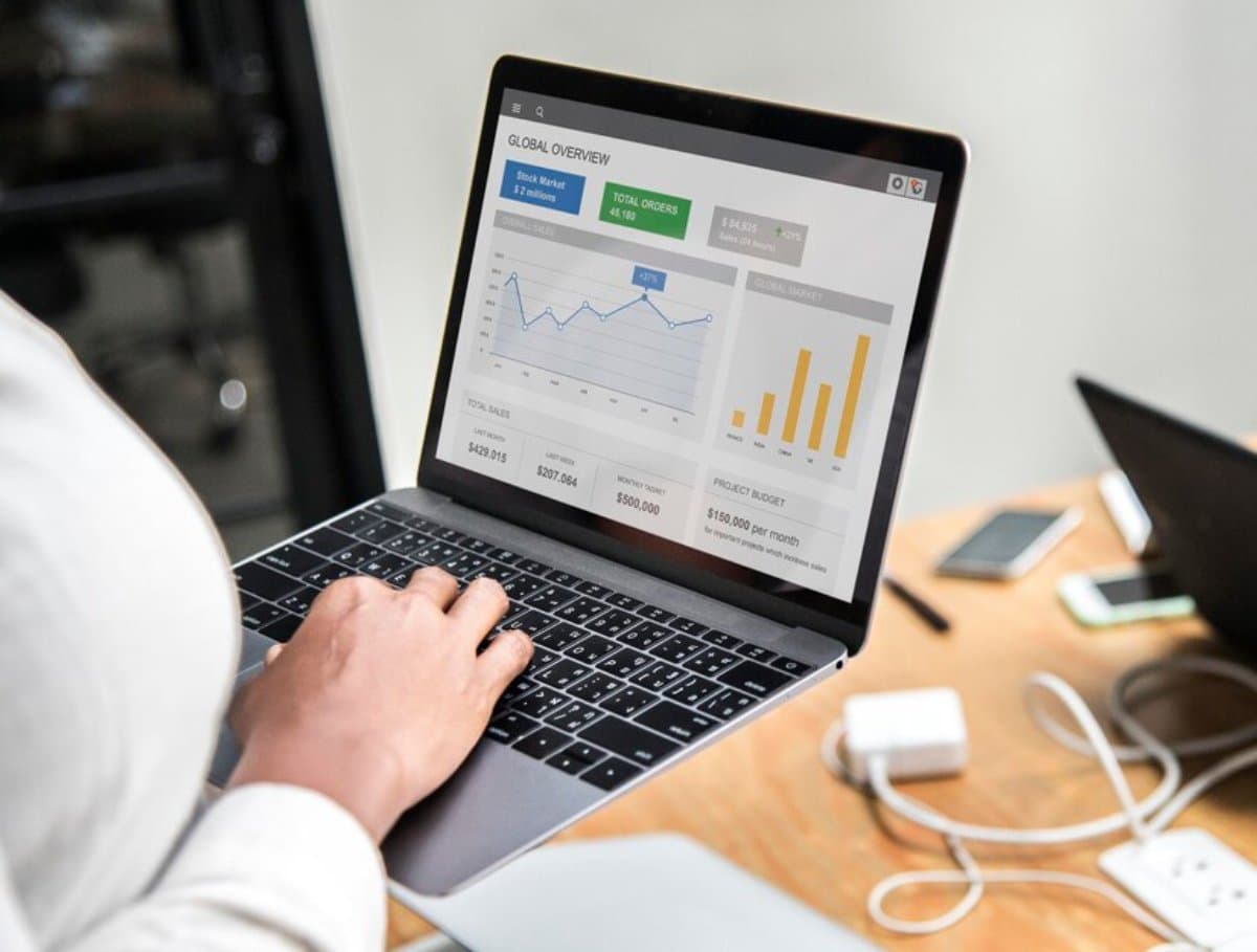 Person working on a laptop displaying graphs and charts for business analysis.