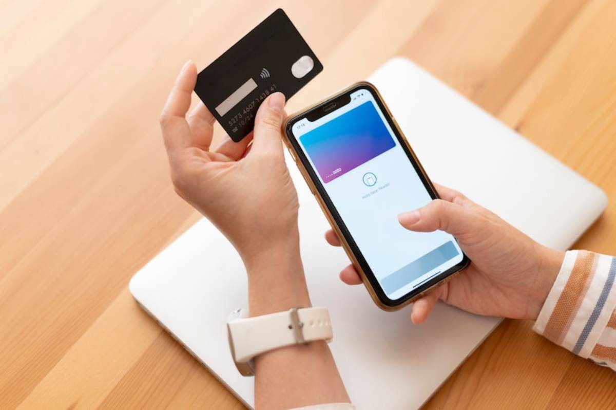 Person holding a credit card in one hand and a smartphone and paying with mobile wallet.