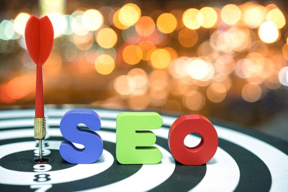 A dart embedded in the bullseye of a target, with colorful wooden letters spelling "SEO" in front.